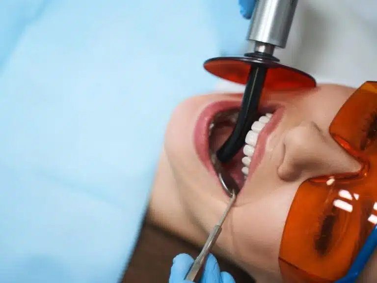 A patient under a curing lamp after getting composite veneers
