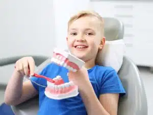 A young boy being shown how to properly brush his teeth by our childrens dentist